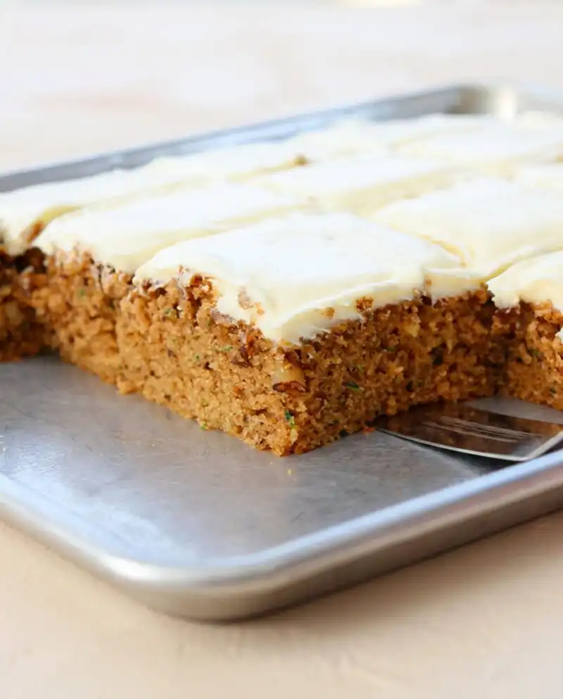 A golden brown zucchini spice cake cooling on a rustic wooden table.